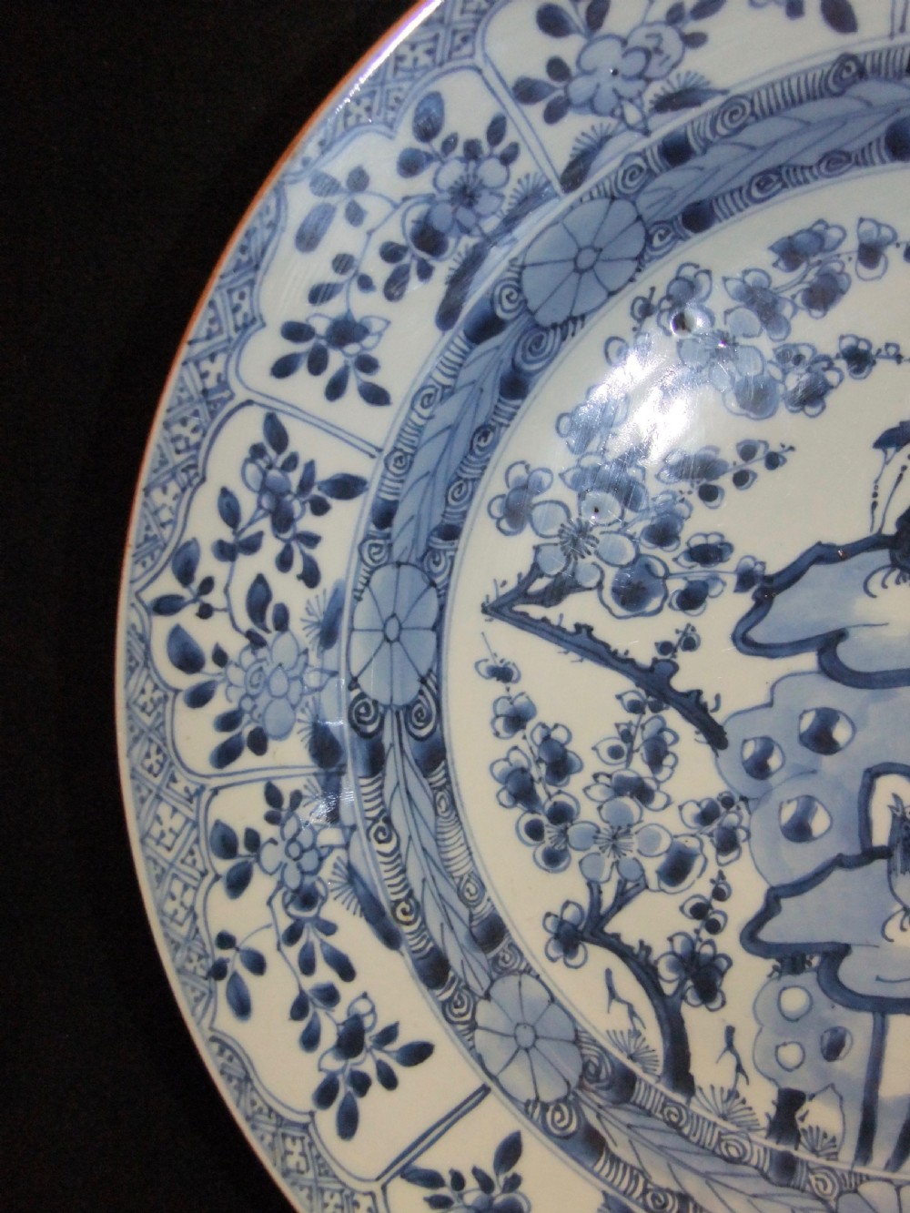A circular Chinese Kangxi period blue and white porcelain charger featuring hand-painted birds on rockwork surrounded by flowering prunus branches and a decorative panelled border. View VI