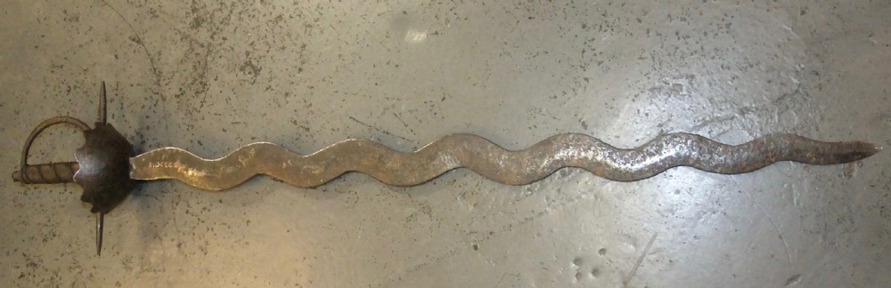 A 17th-century steel cup-hilt sword featuring a long wavy flamberge blade and a rounded metal hand guard. View XVIII