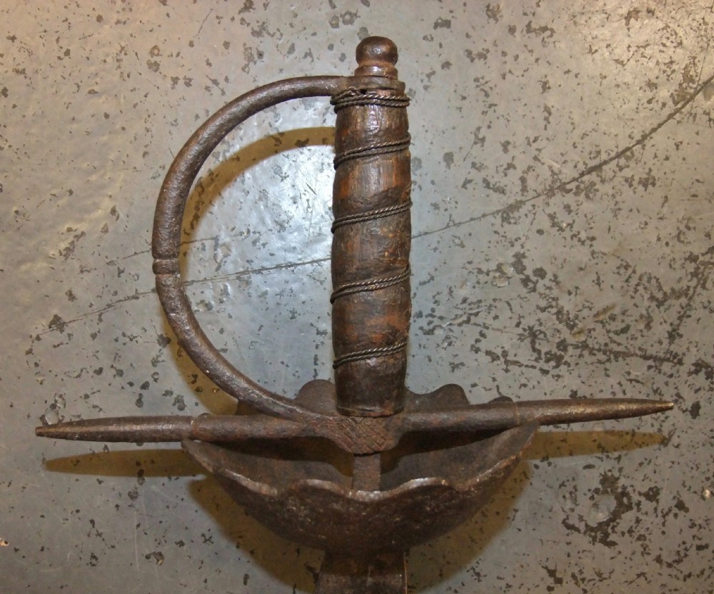 A 17th-century steel cup-hilt sword featuring a long wavy flamberge blade and a rounded metal hand guard. View XX