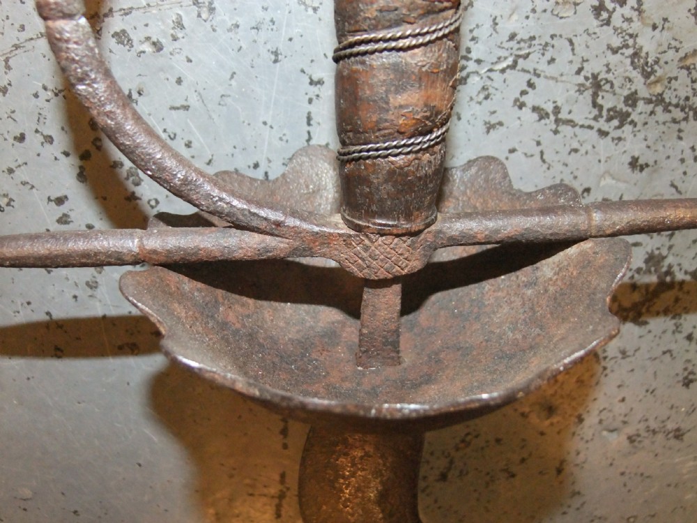 A 17th-century steel cup-hilt sword featuring a long wavy flamberge blade and a rounded metal hand guard. View XXI