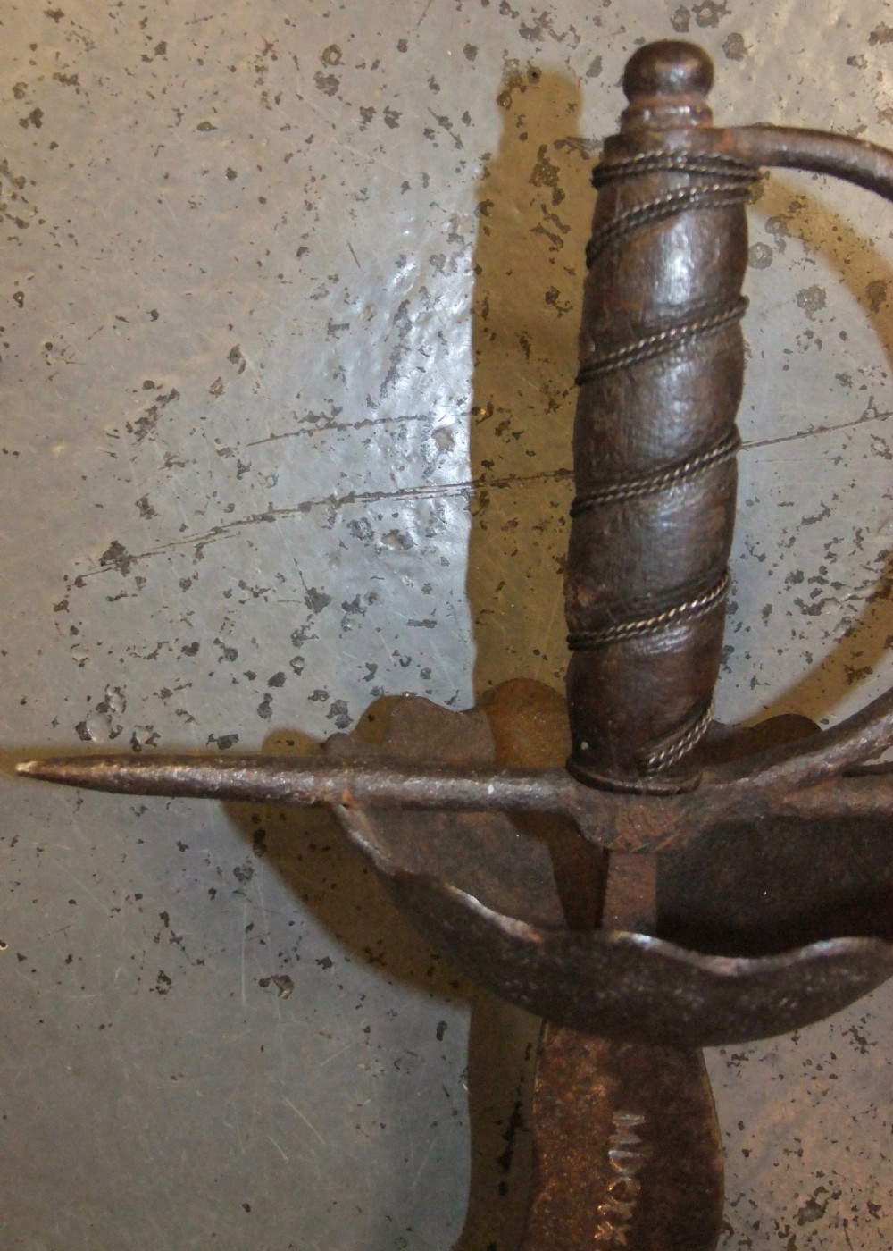 A 17th-century steel cup-hilt sword featuring a long wavy flamberge blade and a rounded metal hand guard. View XXVI