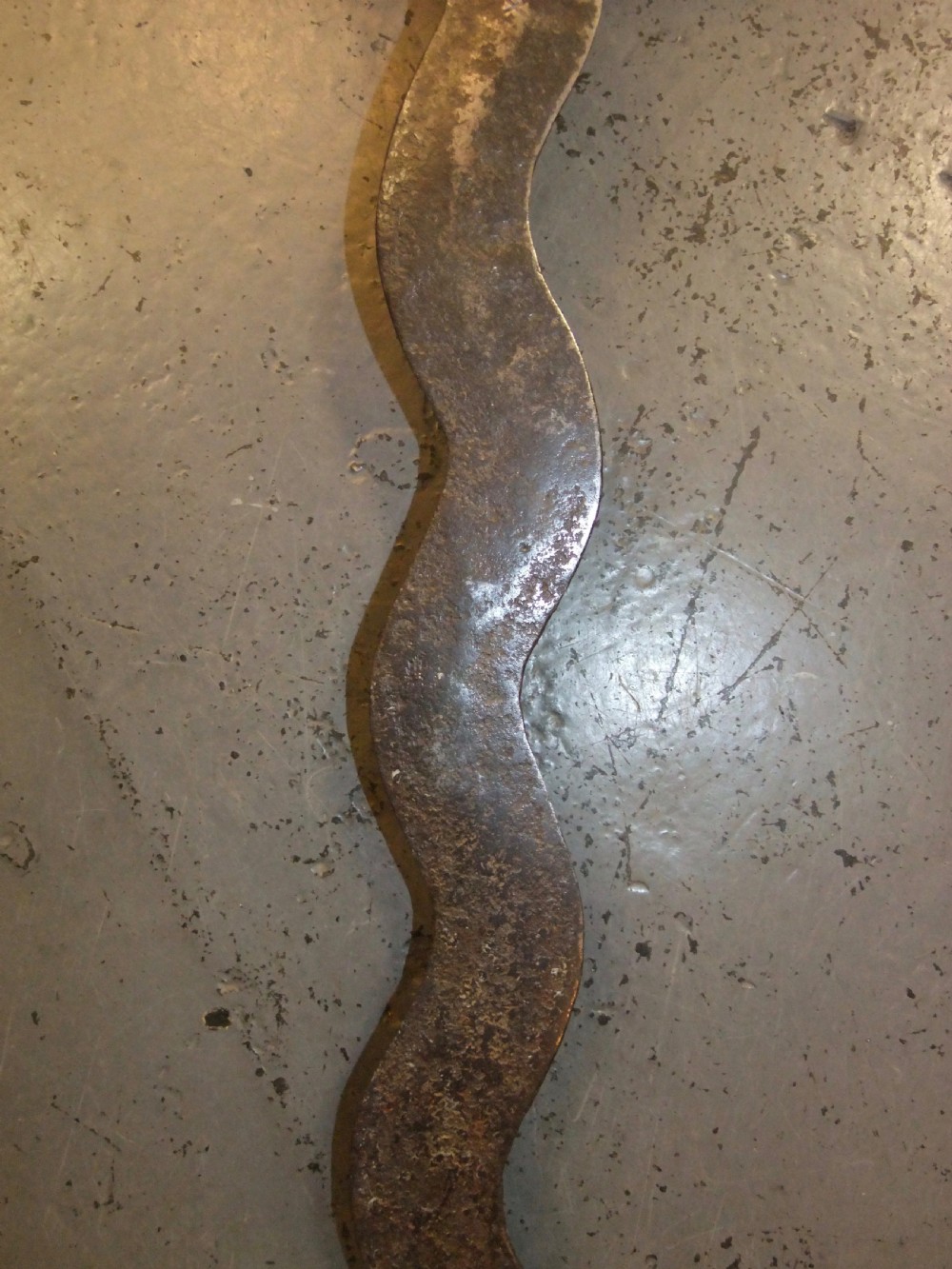 A 17th-century steel cup-hilt sword featuring a long wavy flamberge blade and a rounded metal hand guard. View XXVIII
