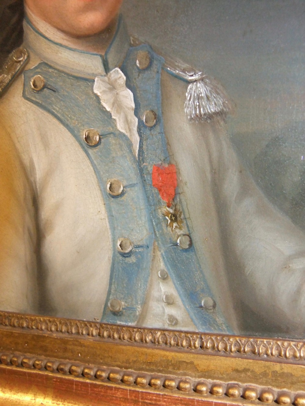 An 18th-century oil portrait depicting a male military officer in a white and blue uniform inside a molded gold gilded frame. View III