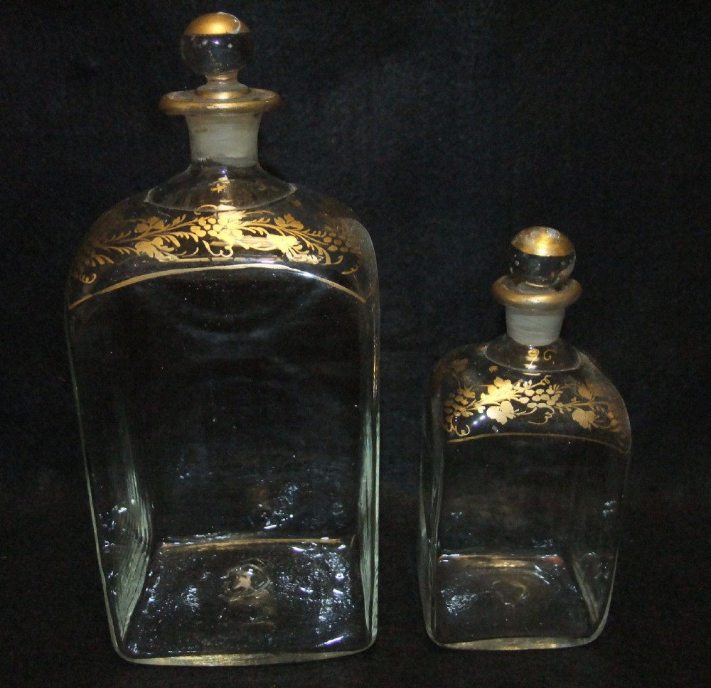 An open wooden campaign box with a blue patterned fabric lining containing ten gilded glass decanters and matching glass stoppers. View VII