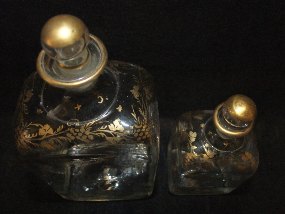 An open wooden campaign box with a blue patterned fabric lining containing ten gilded glass decanters and matching glass stoppers. View VIII