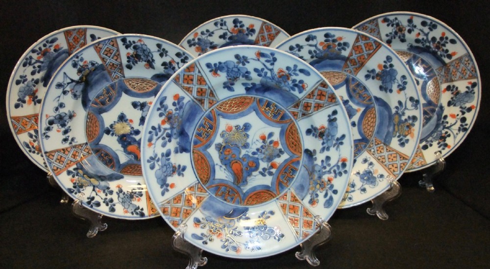 A set of six Chinese Imari porcelain plates featuring cobalt blue, iron red, and gilded floral motifs.