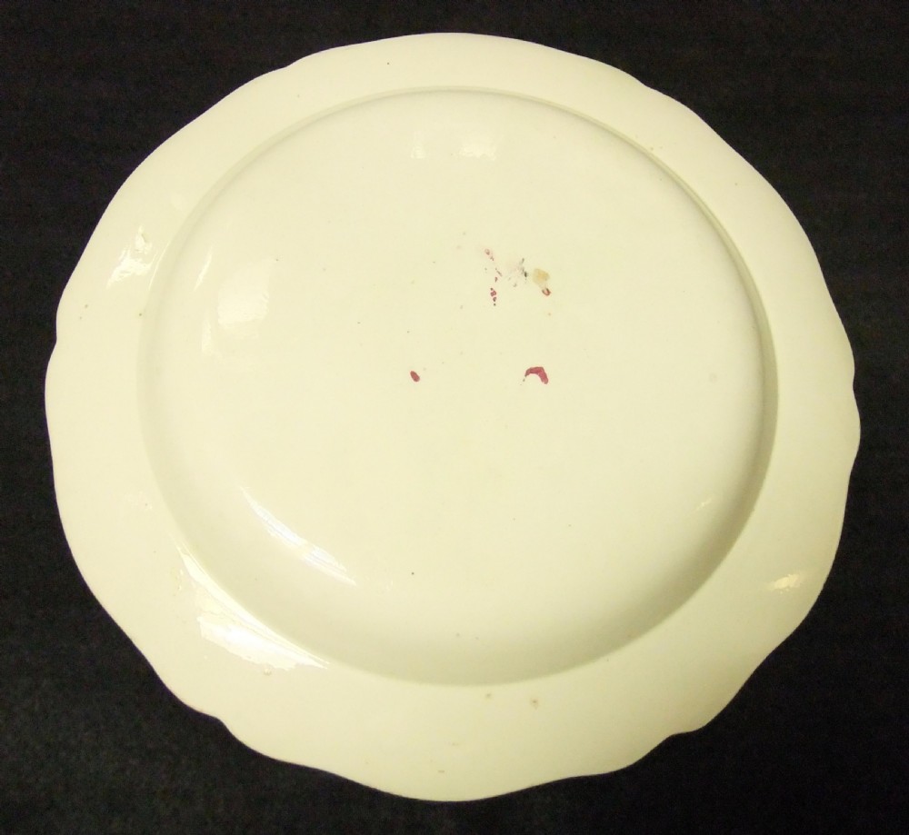 A set of six cream-coloured earthenware plates decorated with hand-painted scenes of the Crucifixion and floral scroll borders along scalloped rims. View III
