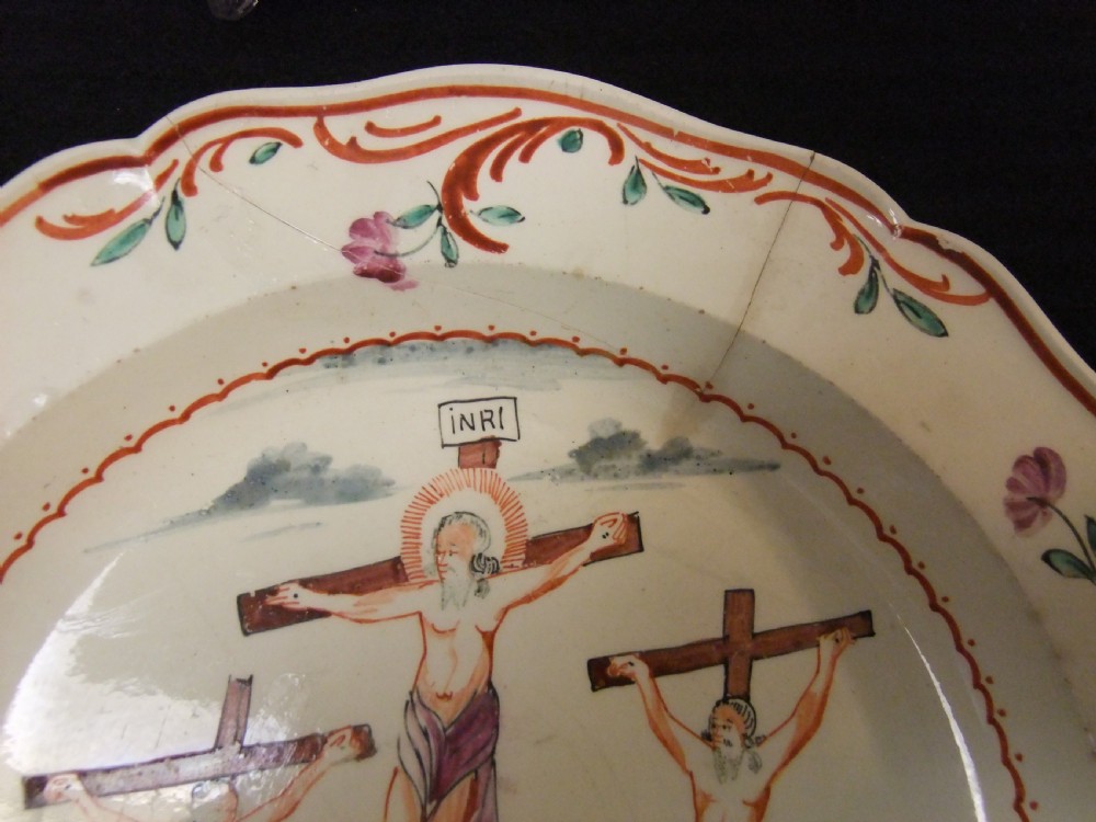 A set of six cream-coloured earthenware plates decorated with hand-painted scenes of the Crucifixion and floral scroll borders along scalloped rims. View IV
