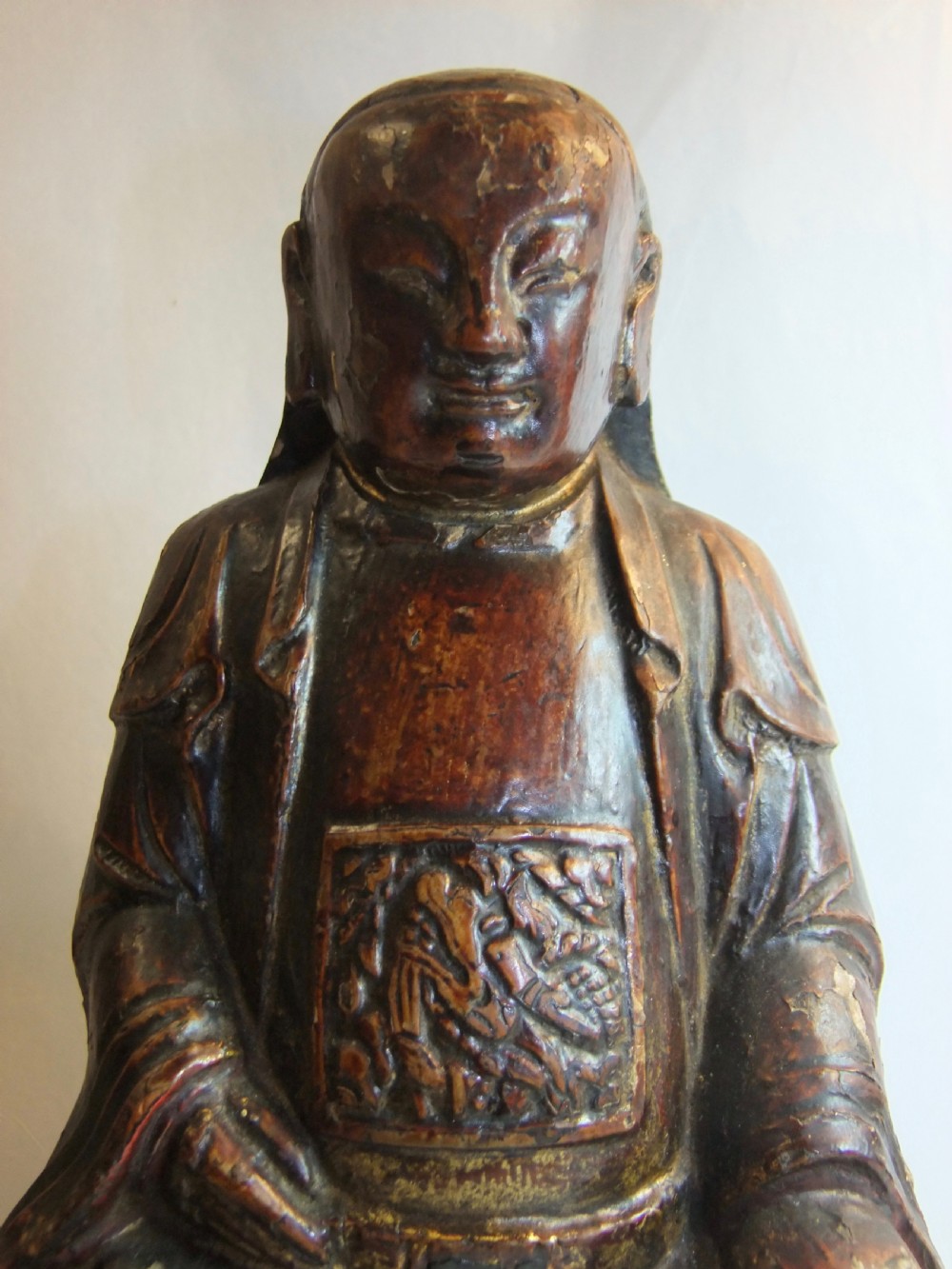 An antique Chinese hand-carved dark wood statue depicting a seated figure in traditional Qing Dynasty robes with traces of gilding and red lacquer. View II