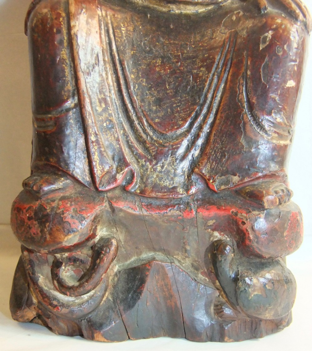 An antique Chinese hand-carved dark wood statue depicting a seated figure in traditional Qing Dynasty robes with traces of gilding and red lacquer. View IV