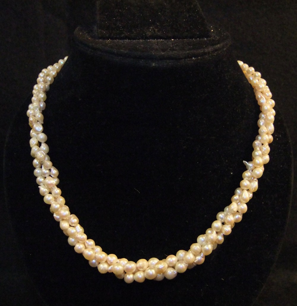 A Victorian three-strand natural pearl necklace featuring cream-coloured pearls woven together.