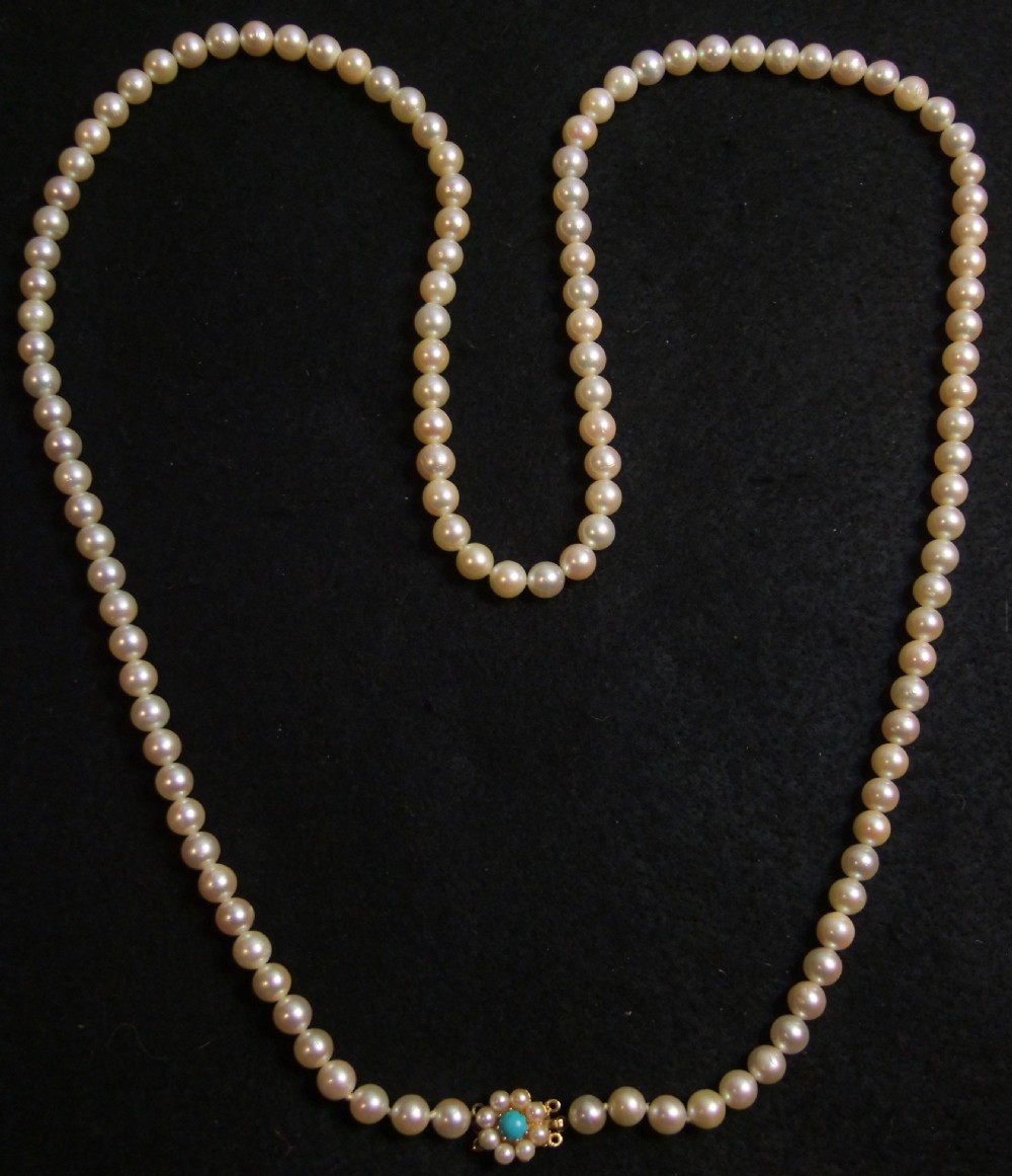 An opera length strand of cream freshwater pearls featuring a flower-shaped gold clasp set with a cabochon turquoise centre. View V