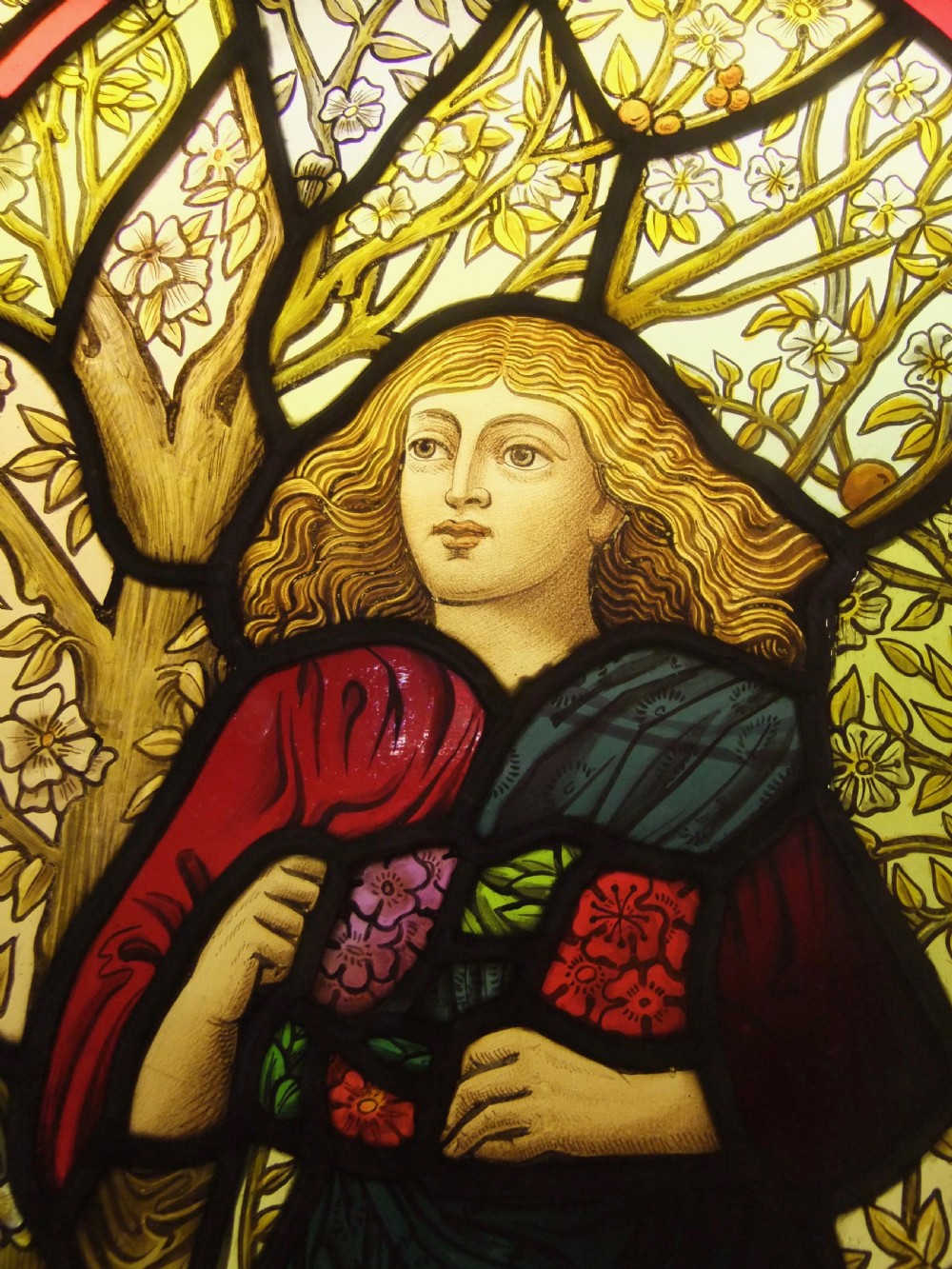 A Pre-Raphaelite stained glass panel featuring a draped female figure surrounded by blossoms and framed by botanical pattern tiles. View II
