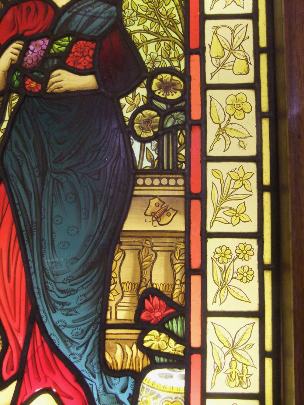 A Pre-Raphaelite stained glass panel featuring a draped female figure surrounded by blossoms and framed by botanical pattern tiles. View III