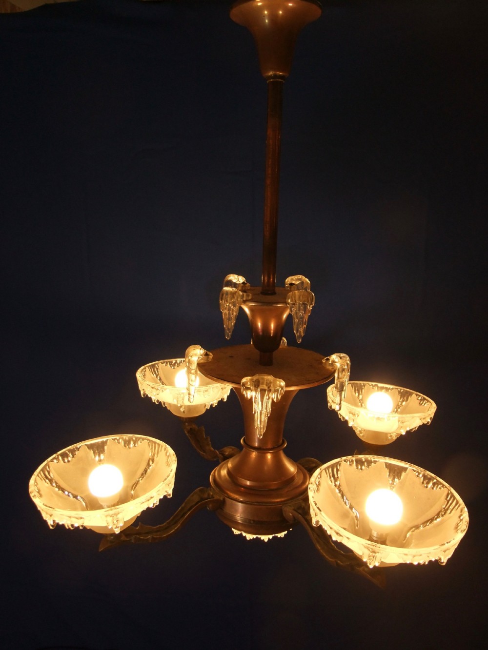 An Art Deco copper chandelier featuring a flared central stem, decorative glass icicle motifs, and four frosted glass shades fitted with light bulbs. View II