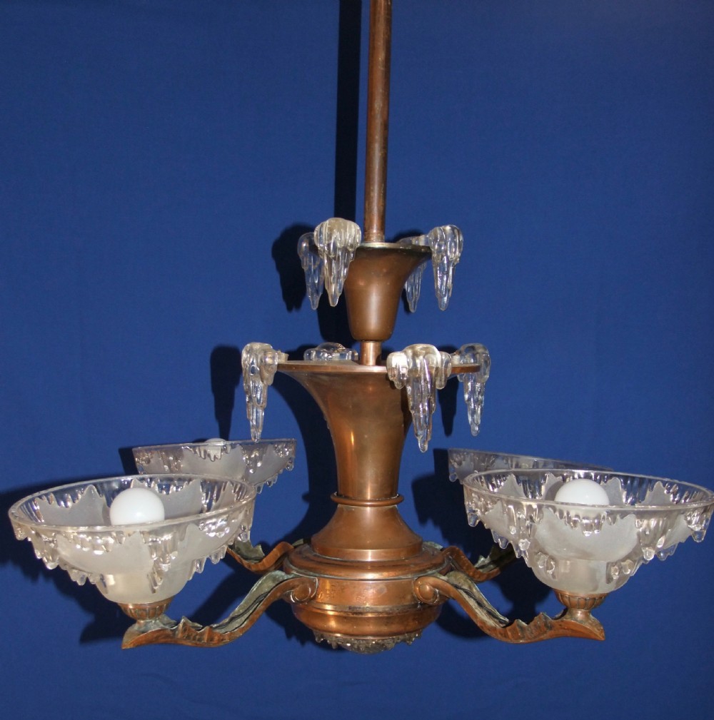 An Art Deco copper chandelier featuring a flared central stem, decorative glass icicle motifs, and four frosted glass shades fitted with light bulbs. View VI