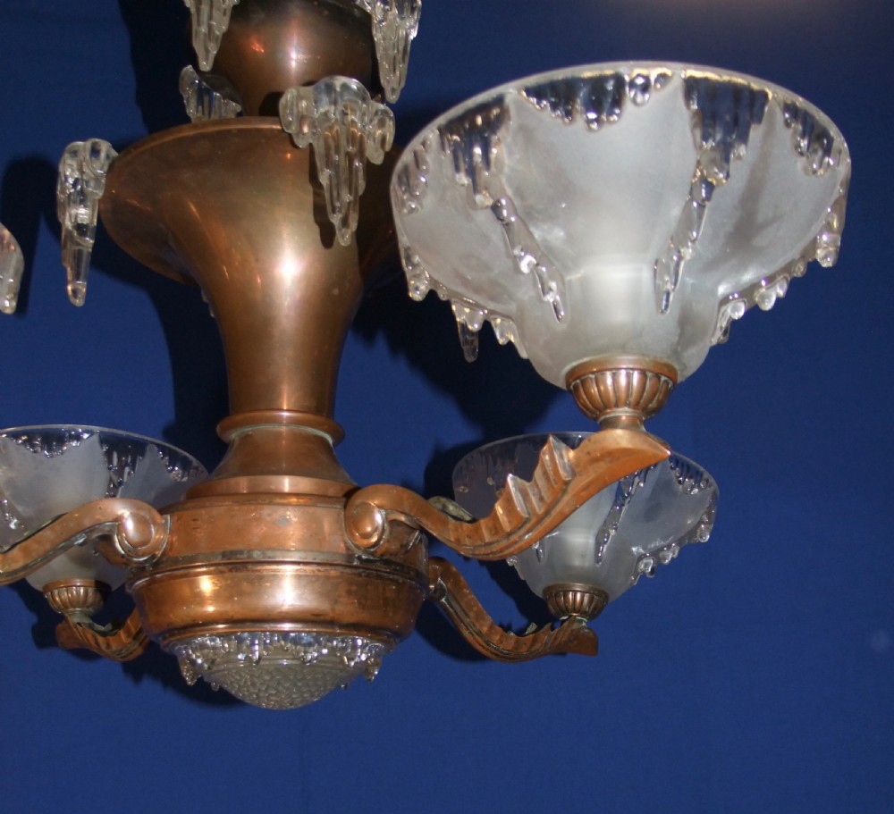 An Art Deco copper chandelier featuring a flared central stem, decorative glass icicle motifs, and four frosted glass shades fitted with light bulbs. View VII