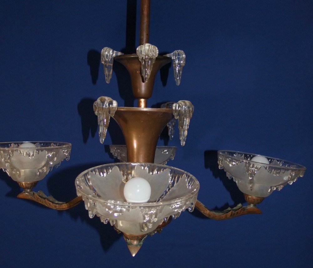An Art Deco copper chandelier featuring a flared central stem, decorative glass icicle motifs, and four frosted glass shades fitted with light bulbs. View X