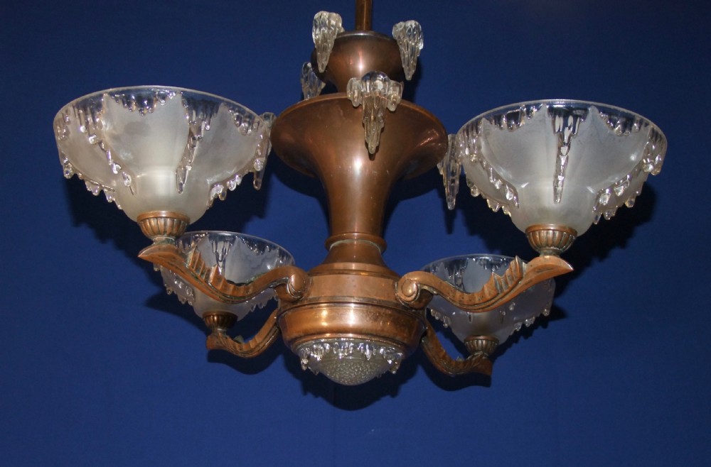 An Art Deco copper chandelier featuring a flared central stem, decorative glass icicle motifs, and four frosted glass shades fitted with light bulbs. View XI