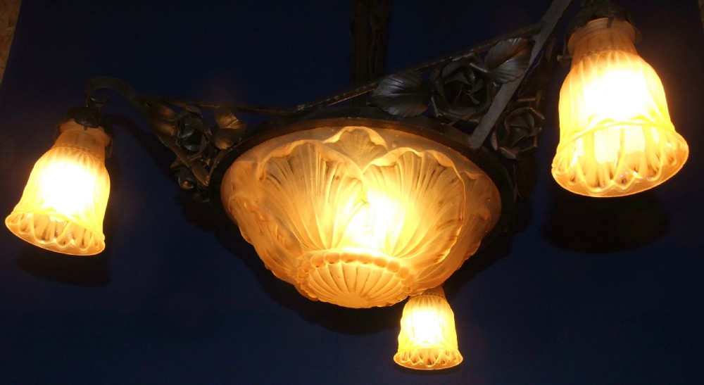An Art Nouveau wrought metal chandelier featuring a central frosted amber glass bowl surrounded by sculpted rose leaves and two suspended glass shades. View II