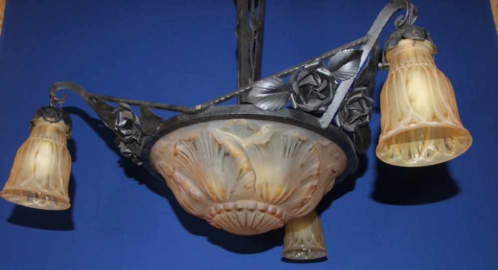An Art Nouveau wrought metal chandelier featuring a central frosted amber glass bowl surrounded by sculpted rose leaves and two suspended glass shades. View V