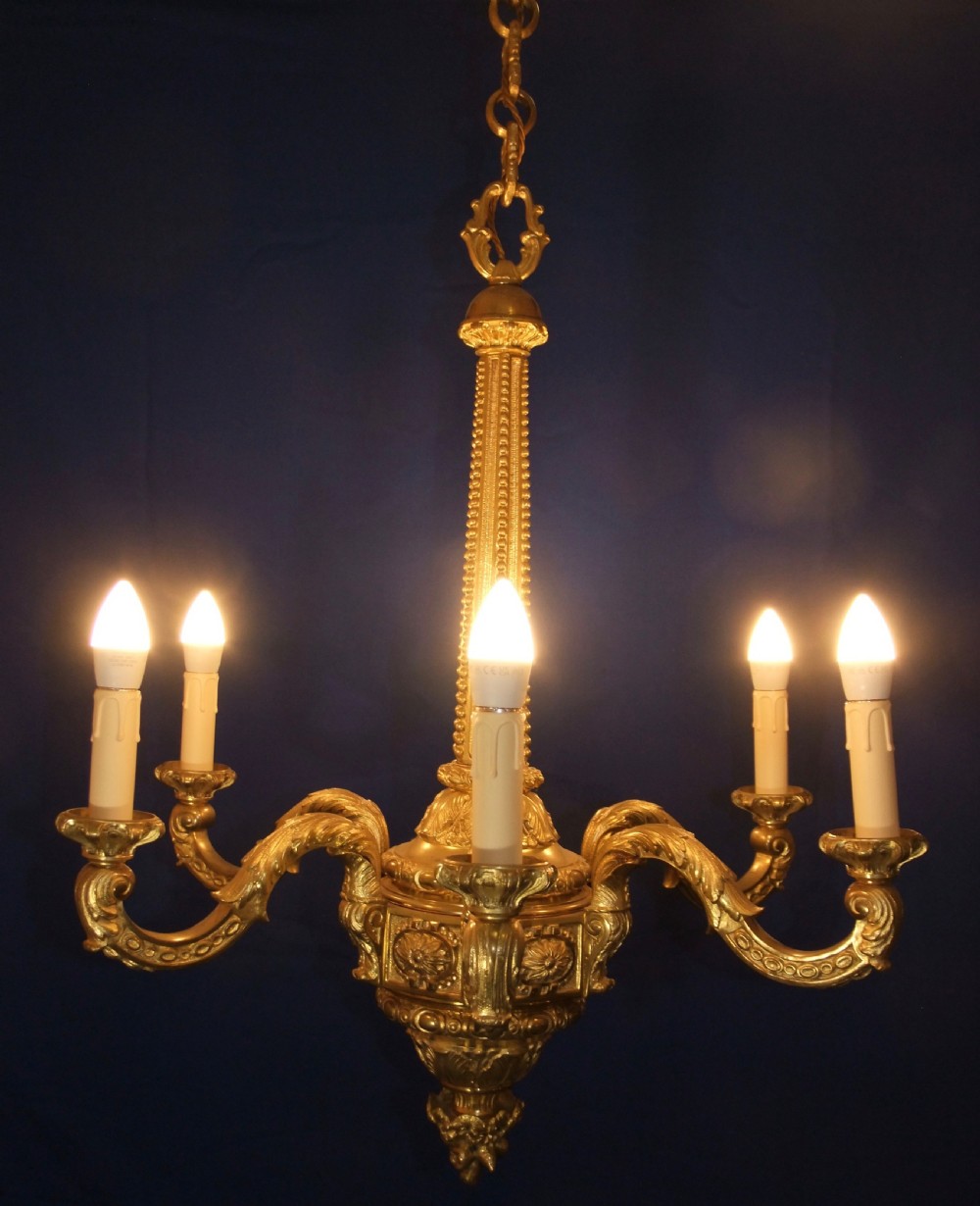 A six-arm gilt bronze chandelier in the Baroque style featuring scrolling arms, acanthus leaf detailing, and candle-style bulb sleeves. View II