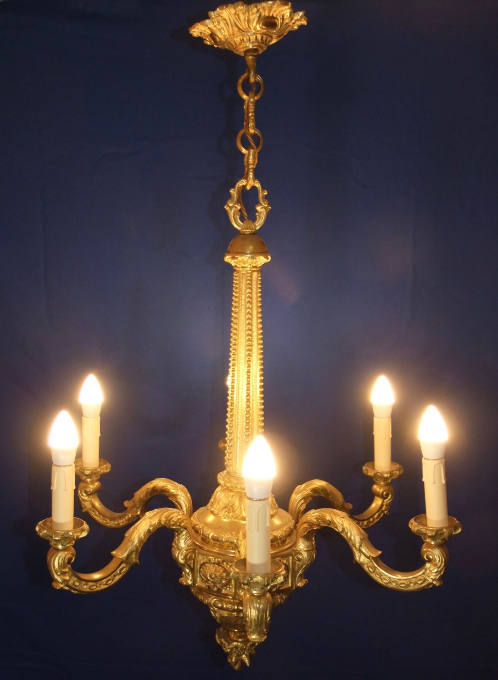 A six-arm gilt bronze chandelier in the Baroque style featuring scrolling arms, acanthus leaf detailing, and candle-style bulb sleeves. View III
