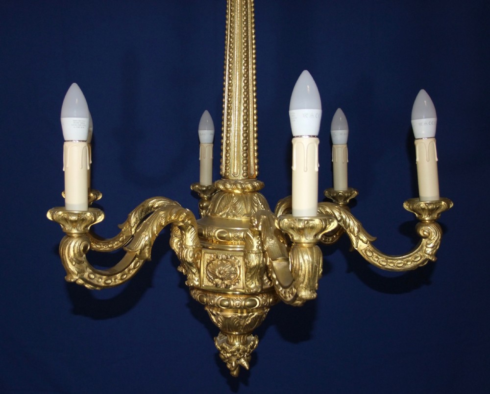A six-arm gilt bronze chandelier in the Baroque style featuring scrolling arms, acanthus leaf detailing, and candle-style bulb sleeves. View V