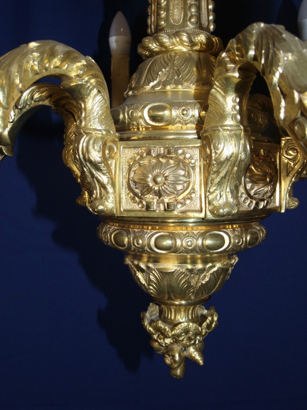 A six-arm gilt bronze chandelier in the Baroque style featuring scrolling arms, acanthus leaf detailing, and candle-style bulb sleeves. View VI