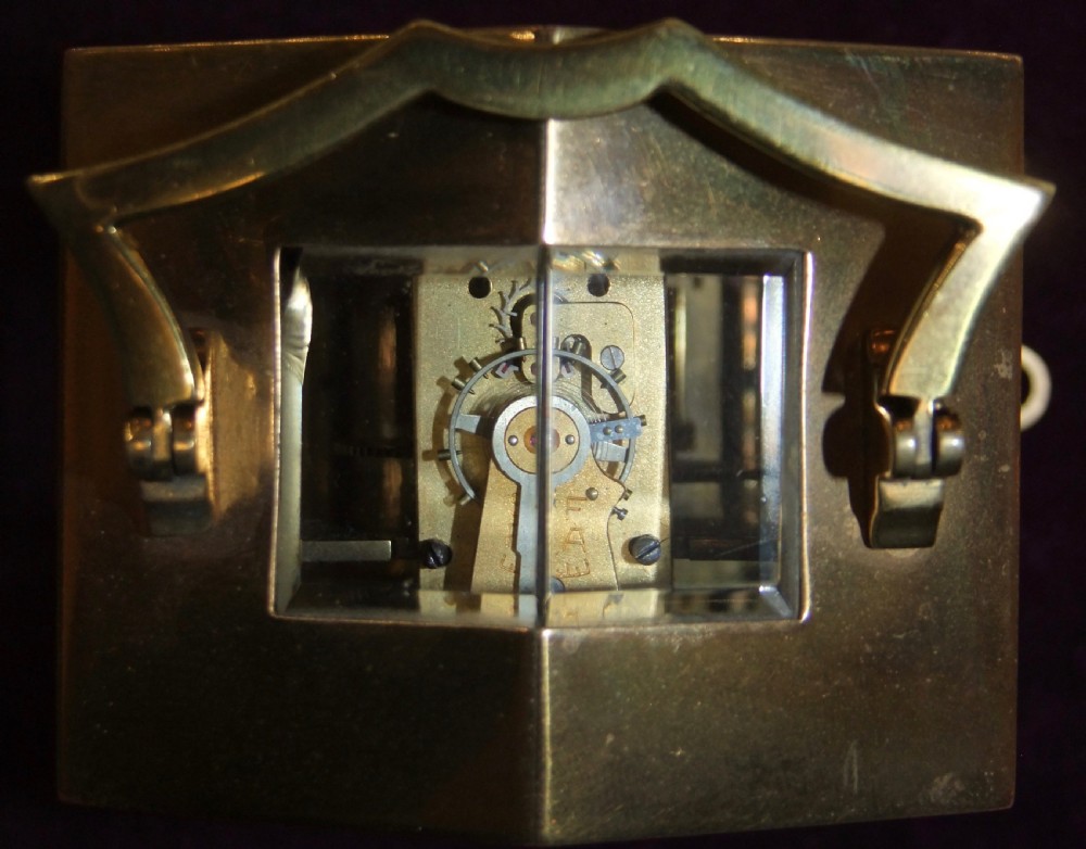 An antique polished brass Georgian revival carriage clock featuring a white dial with Roman numerals, a top carrying handle, and an accompanying winding key. View VII