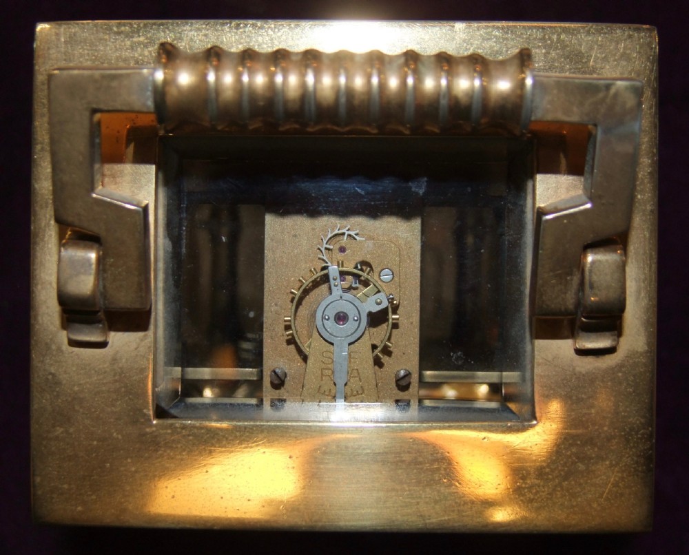 A gilt bronze architectural carriage clock featuring side fluted columns, a reeded carrying handle, compressed bun feet, and a white enamel dial with Roman numerals. View VII