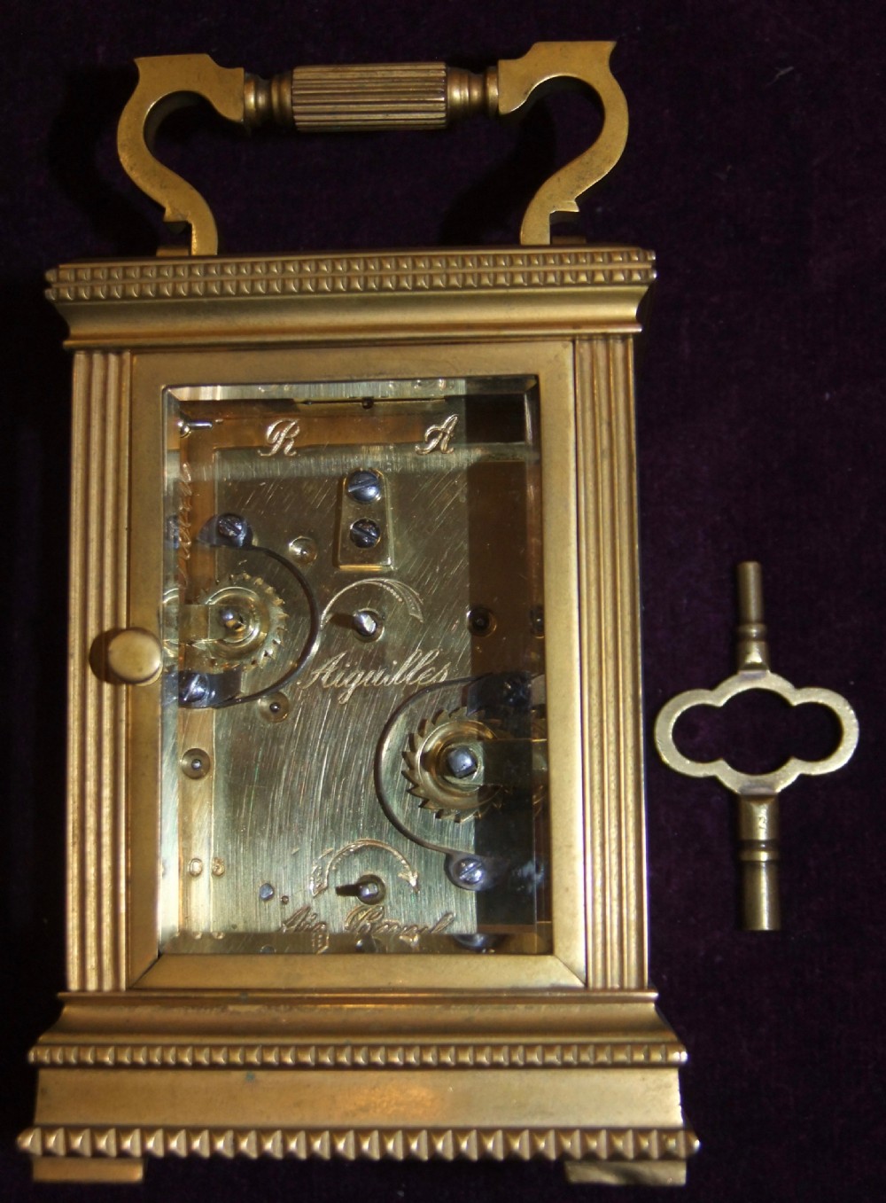 A gilt bronze antique carriage clock featuring a rectangular glass case, top carrying handle, Roman numeral dial, alarm sub-dial, and accompanying winding key. View IV