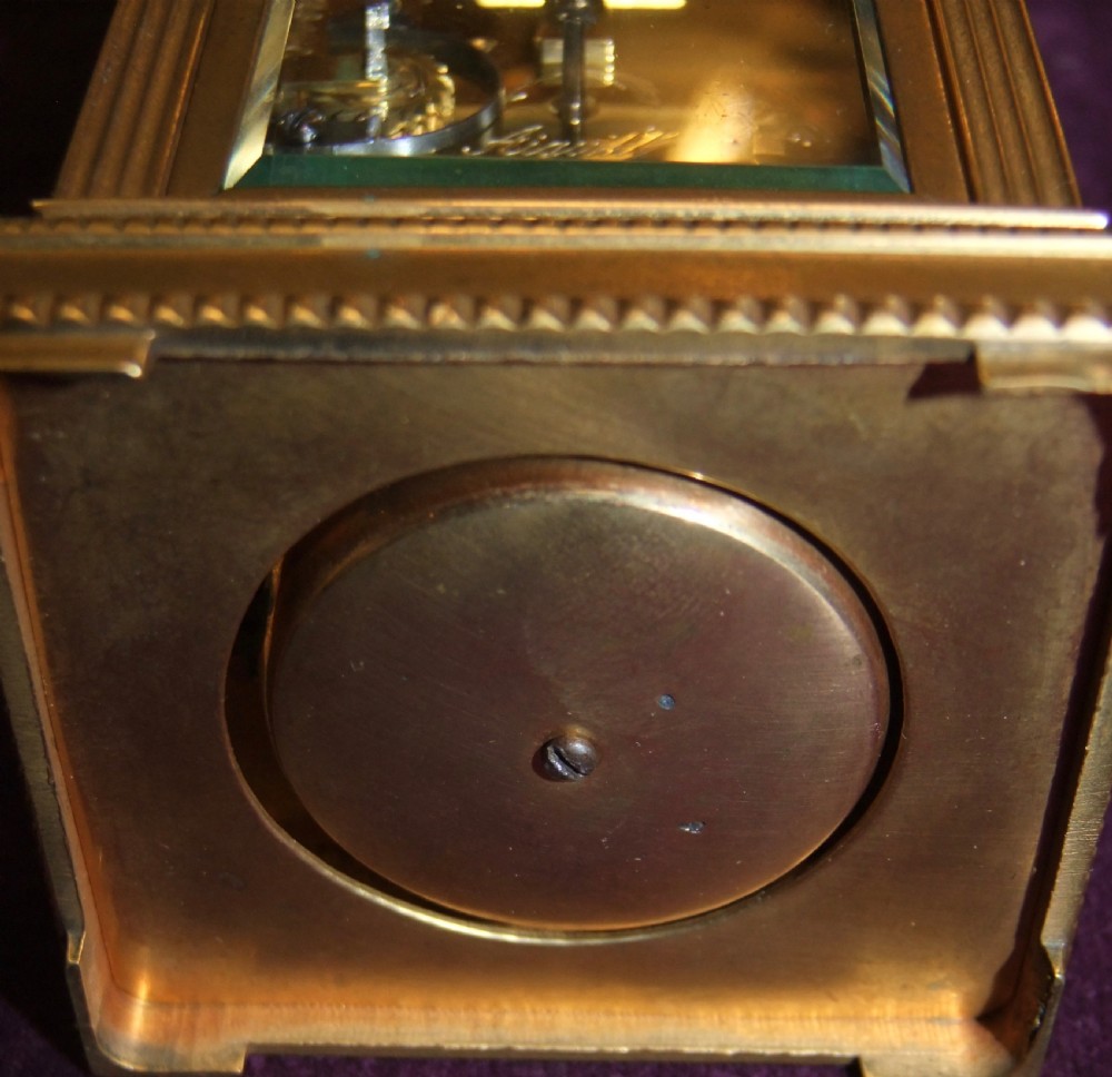 A gilt bronze antique carriage clock featuring a rectangular glass case, top carrying handle, Roman numeral dial, alarm sub-dial, and accompanying winding key. View VI