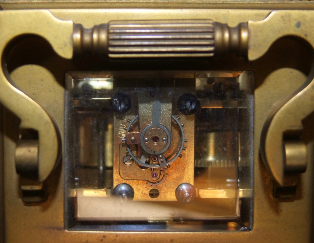 A gilt bronze antique carriage clock featuring a rectangular glass case, top carrying handle, Roman numeral dial, alarm sub-dial, and accompanying winding key. View VII