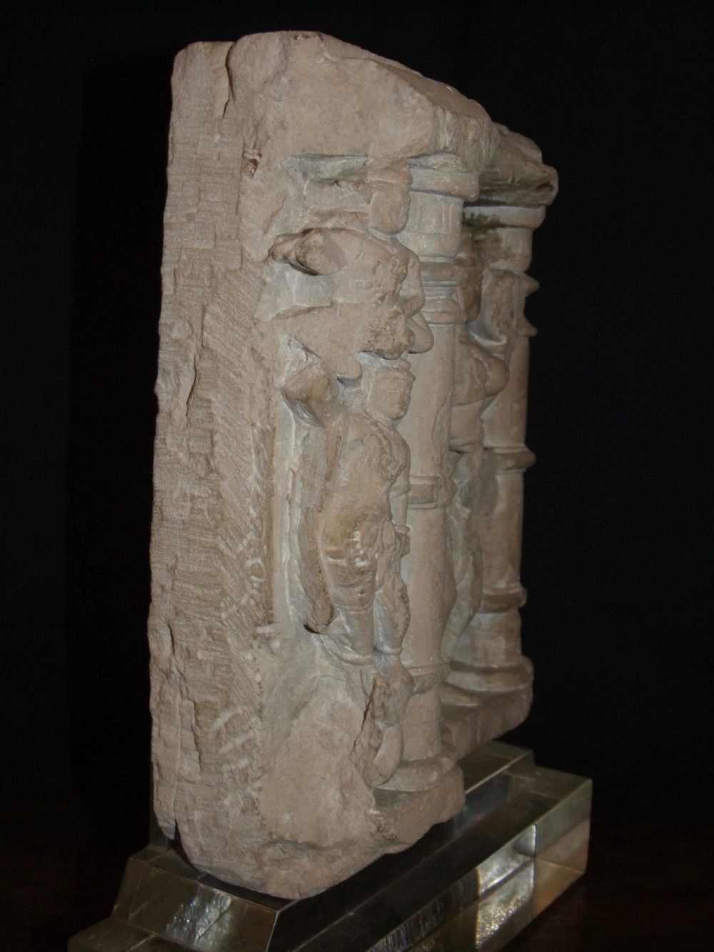 A carved beige sandstone relief fragment from 11th century India depicting the Hindu deity Parvati flanked by decorative columns and smaller attendant figures. View XI