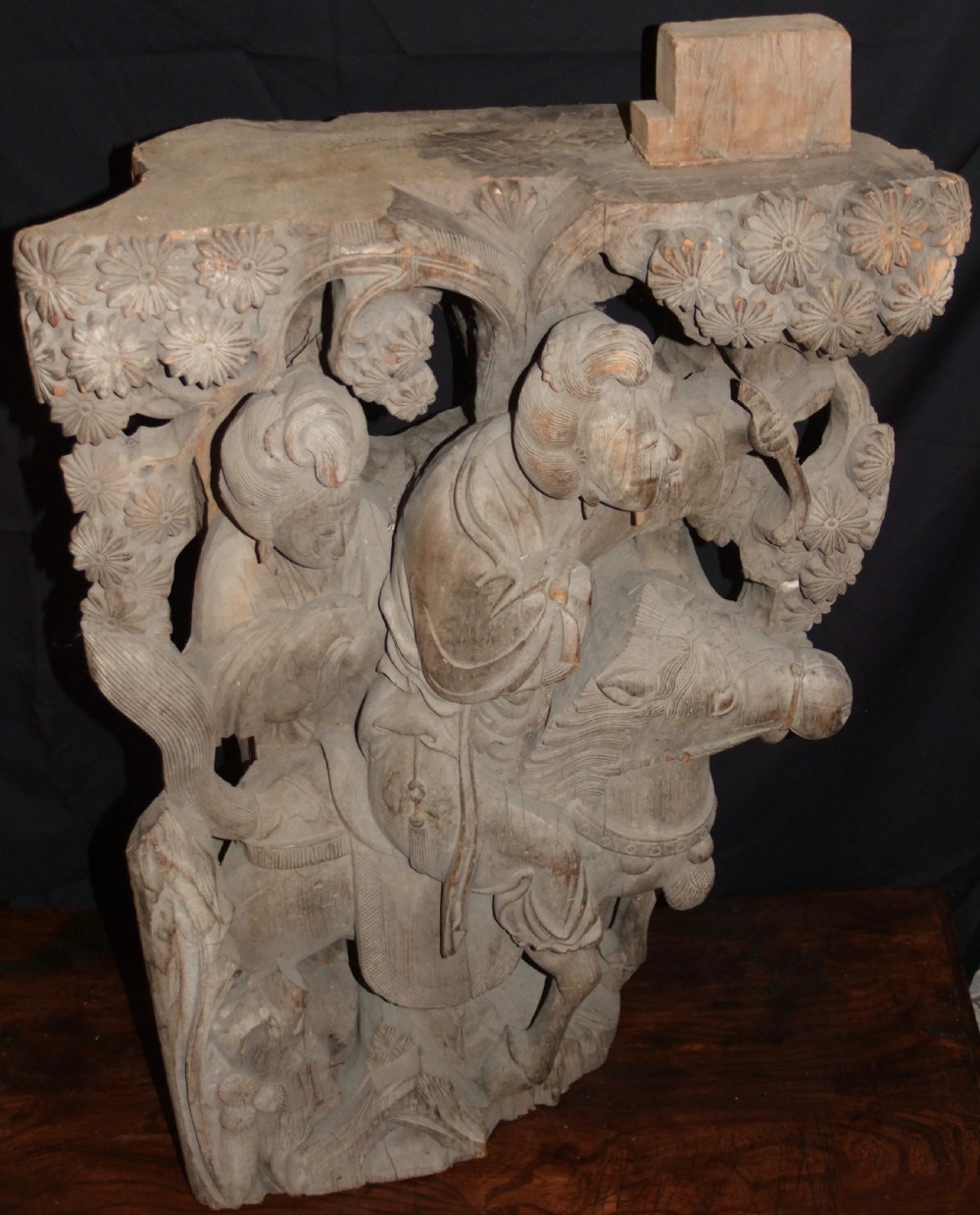 A pair of deeply carved natural timber architectural corbels depicting figures mounted on horses amidst floral motifs. View II