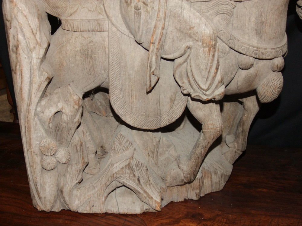 A pair of deeply carved natural timber architectural corbels depicting figures mounted on horses amidst floral motifs. View V