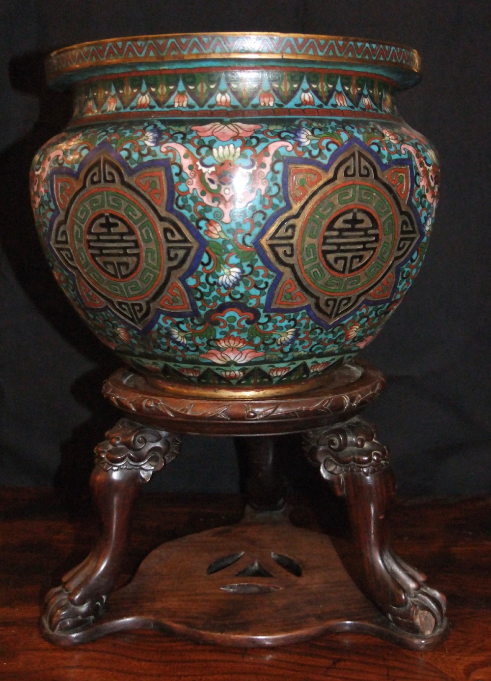 A large Chinese cloisonne enamel jardiniere with floral scrollwork and longevity motifs resting on a dark carved wood stand. View III