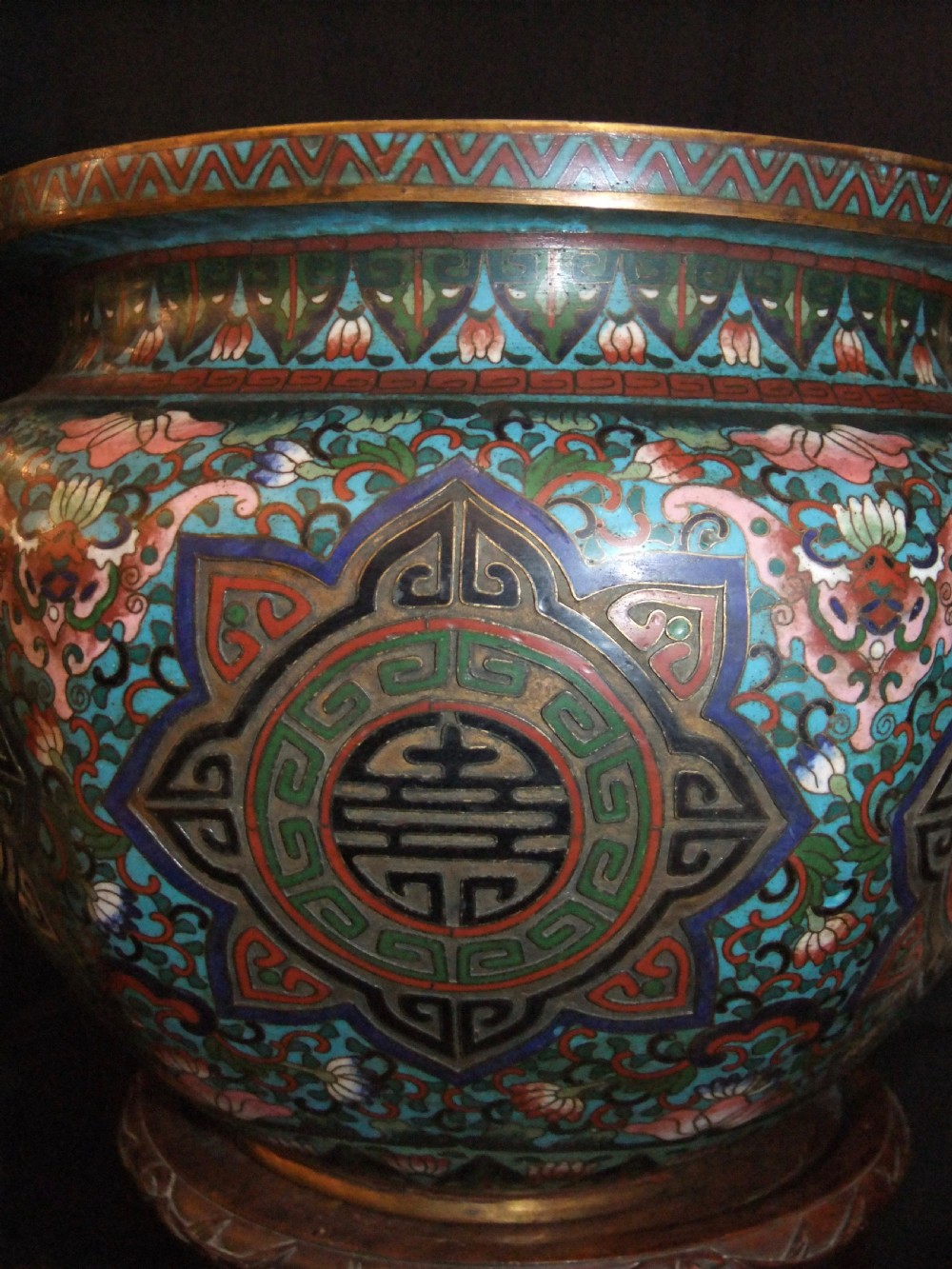 A large Chinese cloisonne enamel jardiniere with floral scrollwork and longevity motifs resting on a dark carved wood stand. View IV