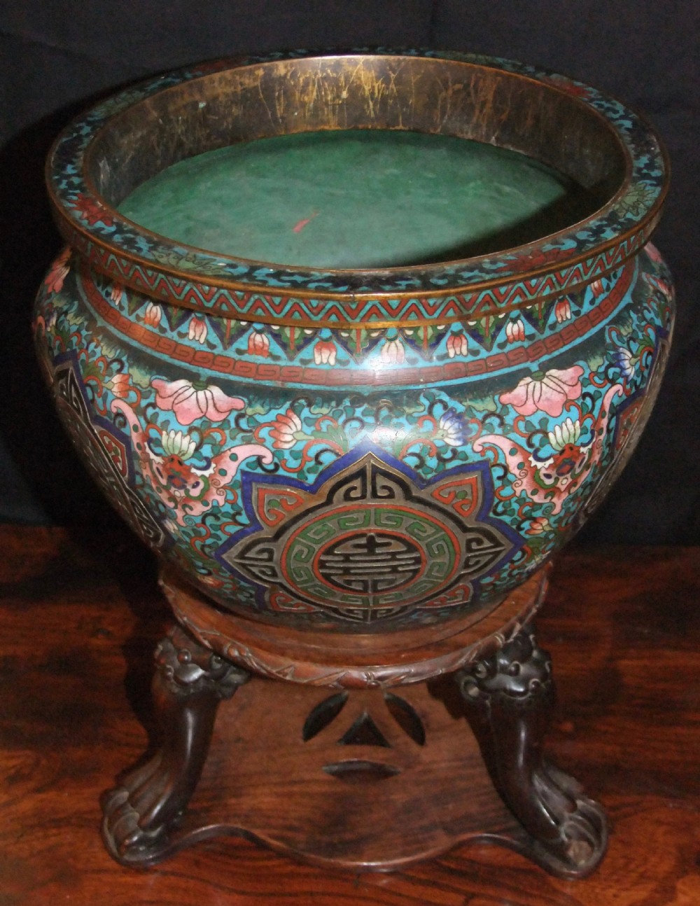 A large Chinese cloisonne enamel jardiniere with floral scrollwork and longevity motifs resting on a dark carved wood stand. View V
