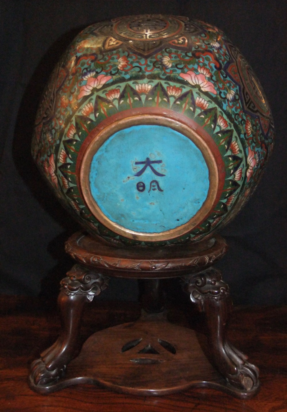 A large Chinese cloisonne enamel jardiniere with floral scrollwork and longevity motifs resting on a dark carved wood stand. View VI