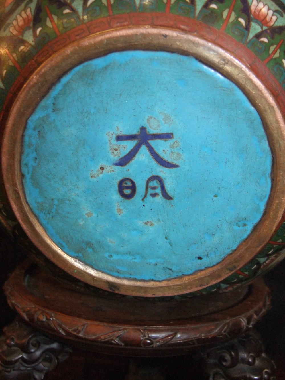 A large Chinese cloisonne enamel jardiniere with floral scrollwork and longevity motifs resting on a dark carved wood stand. View VII