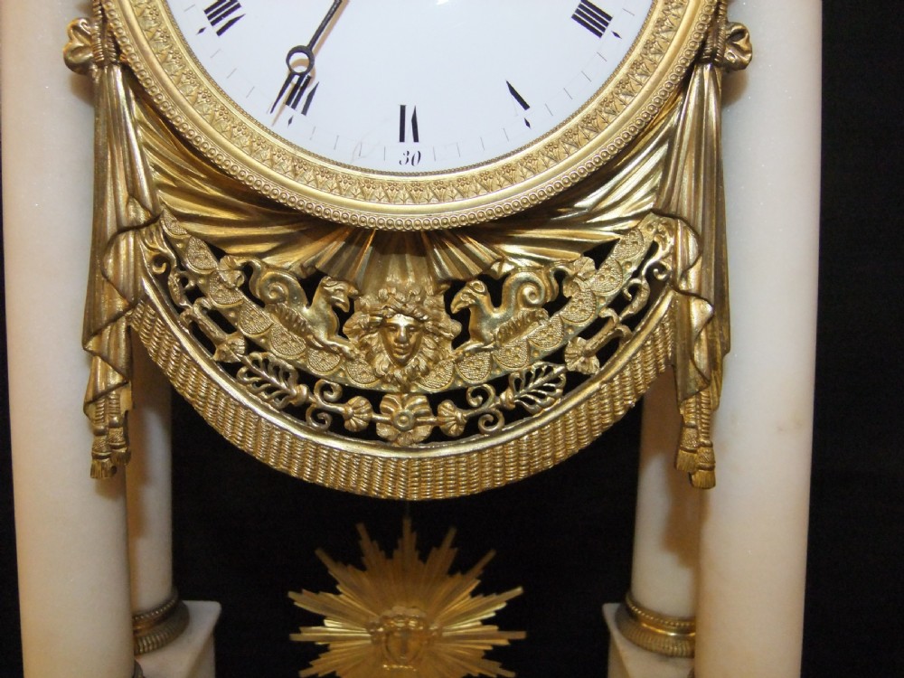 French Directoire period white marble and ormolu portico mantel clock featuring classical columns, a sunburst pendulum, and gilt bronze architectural mounts. View III