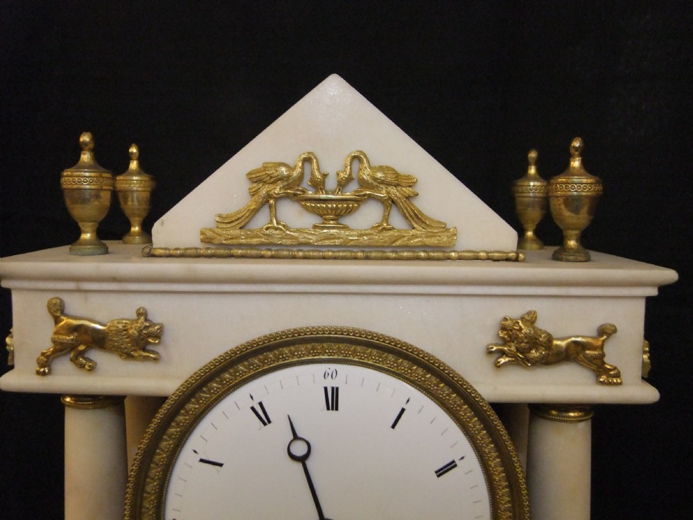 French Directoire period white marble and ormolu portico mantel clock featuring classical columns, a sunburst pendulum, and gilt bronze architectural mounts. View IV