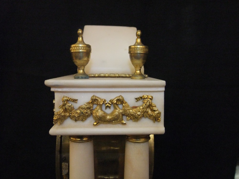 French Directoire period white marble and ormolu portico mantel clock featuring classical columns, a sunburst pendulum, and gilt bronze architectural mounts. View VII