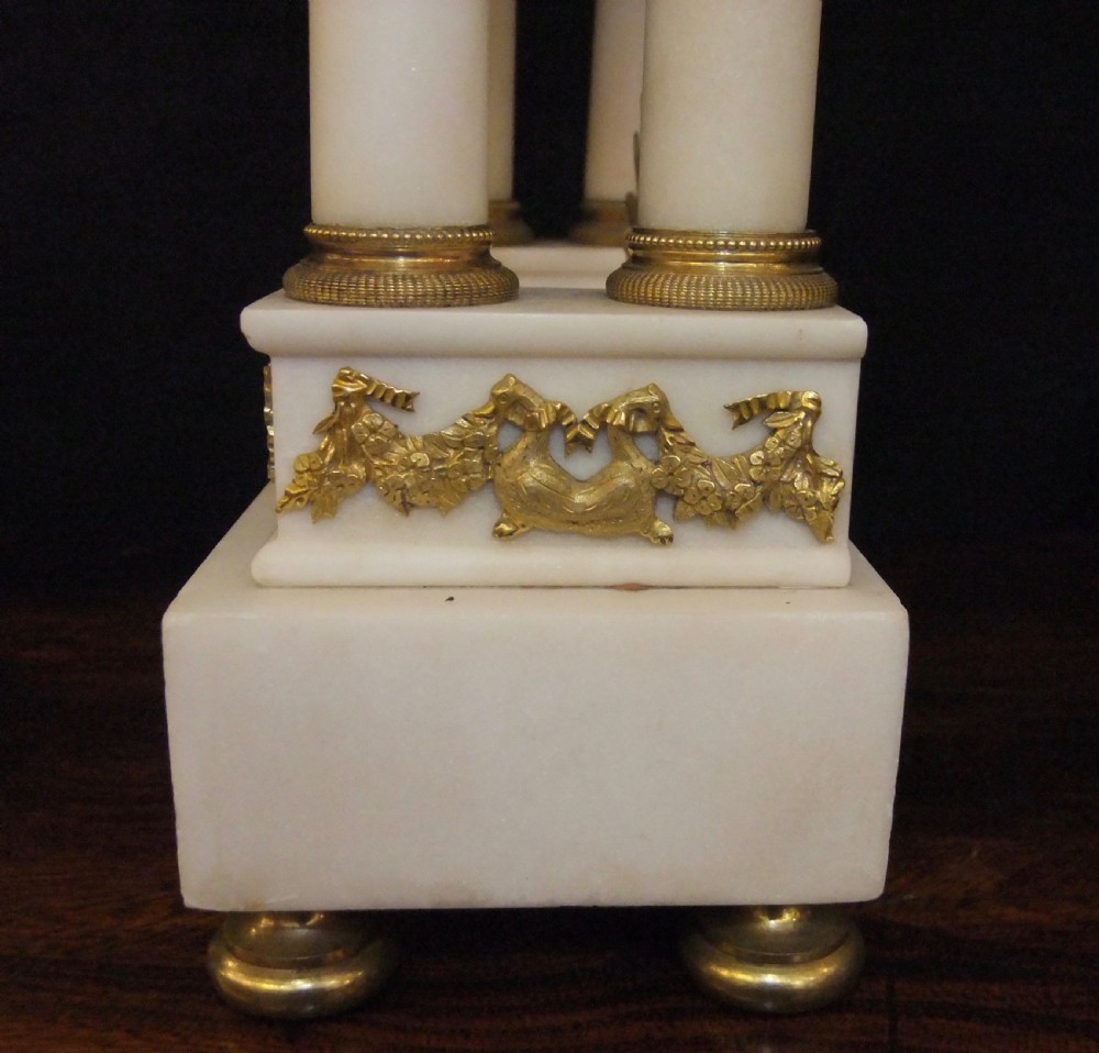 French Directoire period white marble and ormolu portico mantel clock featuring classical columns, a sunburst pendulum, and gilt bronze architectural mounts. View VIII