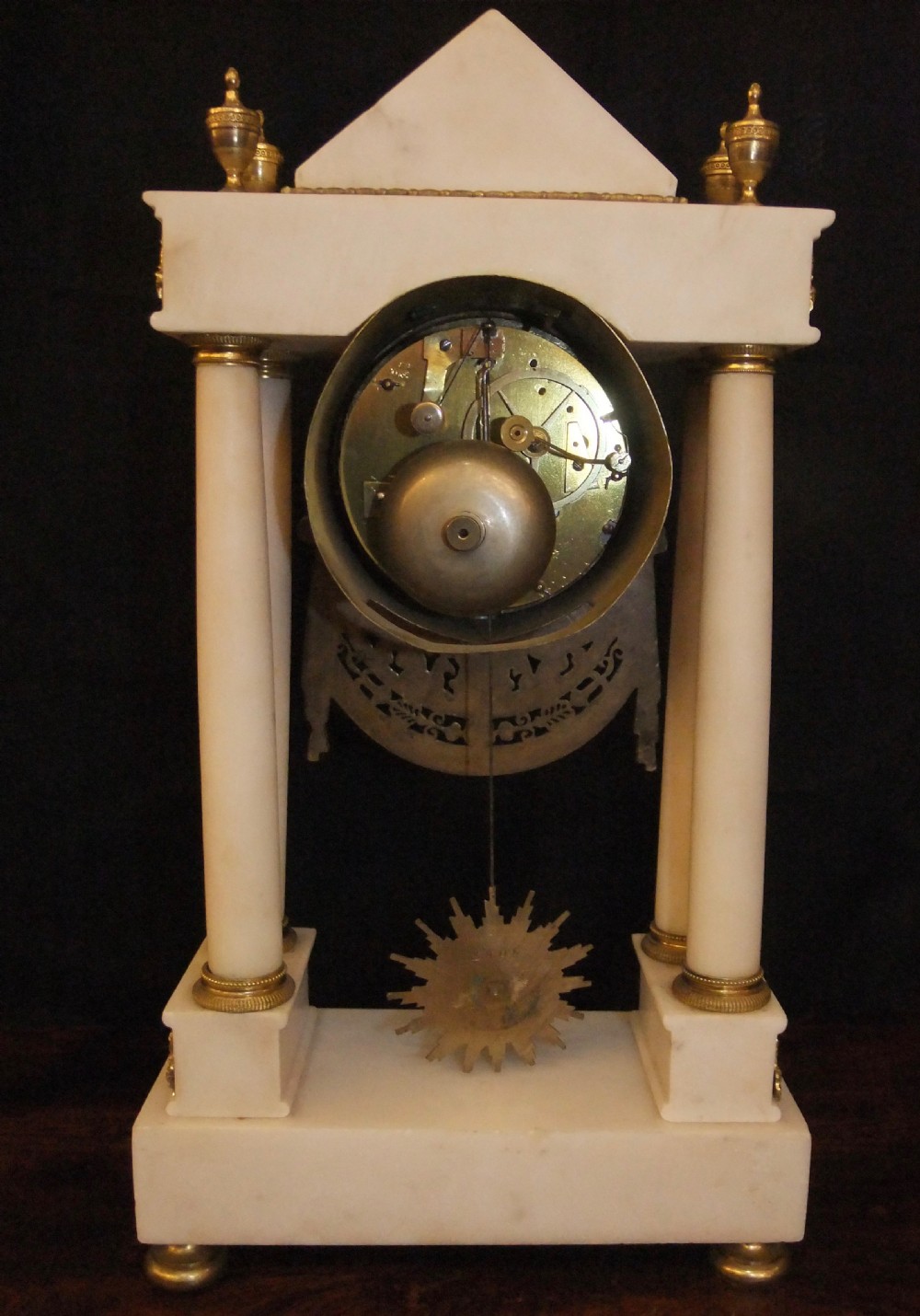 French Directoire period white marble and ormolu portico mantel clock featuring classical columns, a sunburst pendulum, and gilt bronze architectural mounts. View IX