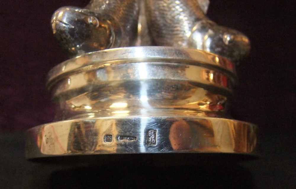 A polished silver goblet featuring a plain round bowl supported by three cast koi carp fish forming the stem above a stepped circular base. View IV