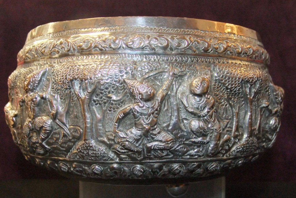 A 19th-century Burmese footed silver bowl featuring high-relief repousse decoration depicting figures, animals, and trees. View II