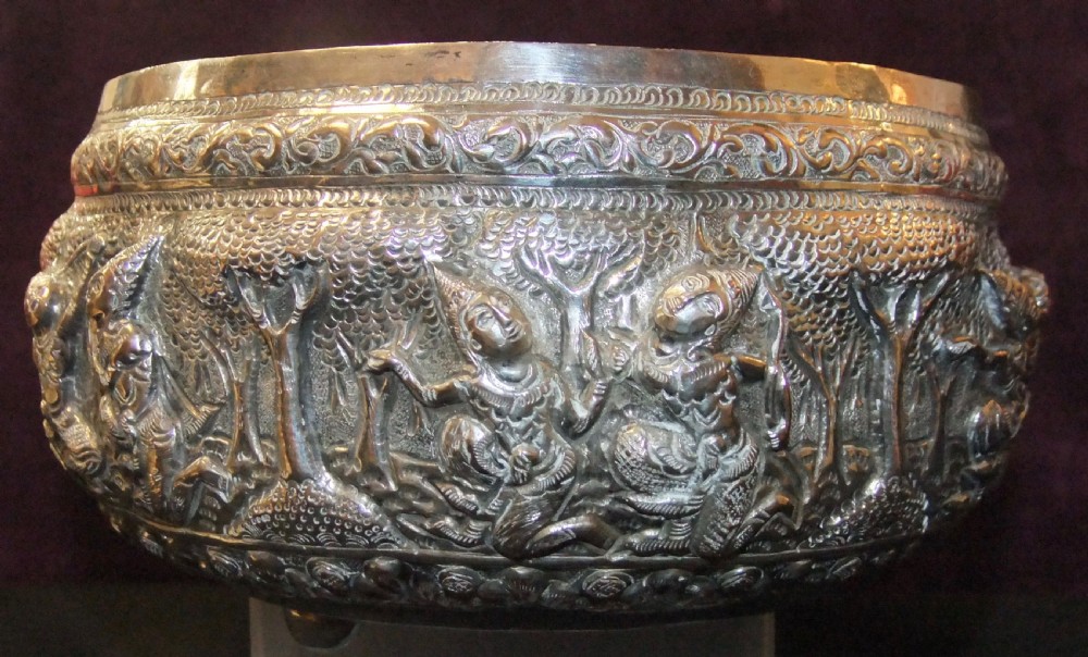 A 19th-century Burmese footed silver bowl featuring high-relief repousse decoration depicting figures, animals, and trees. View III